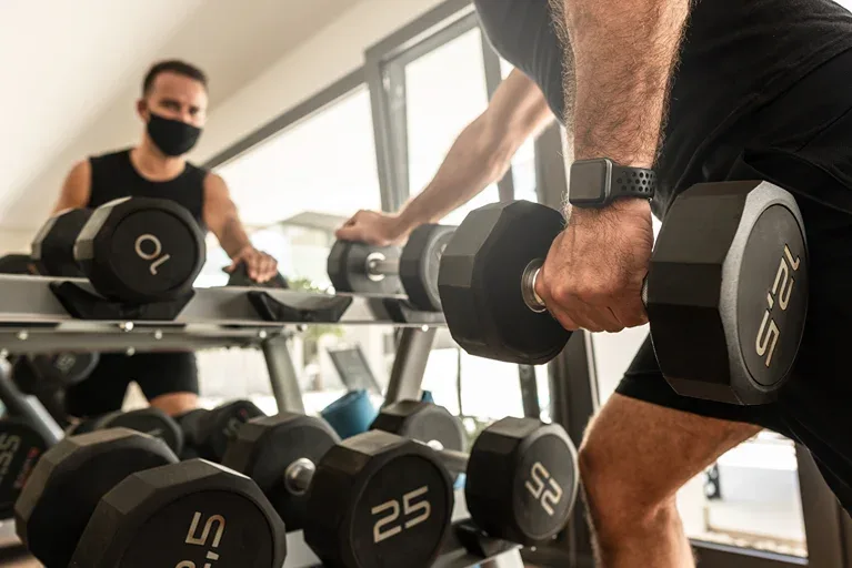 Two men in a gym lifting weights.