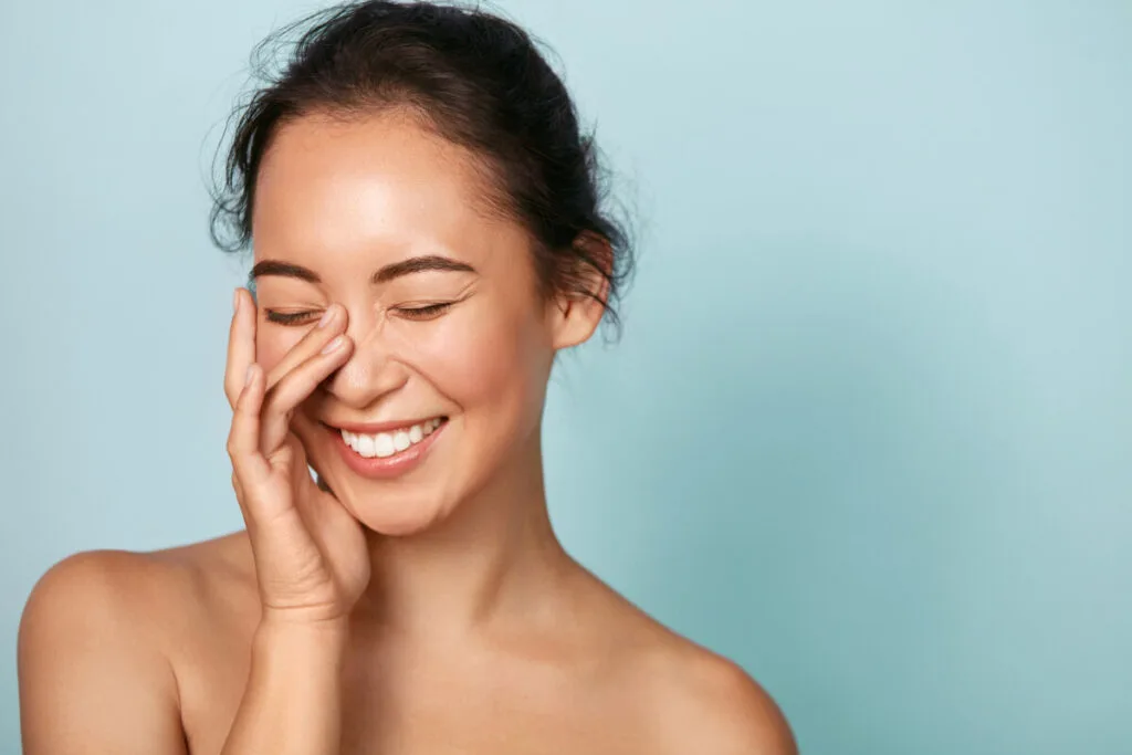 Smiling asian woman touching healthy skin portrait